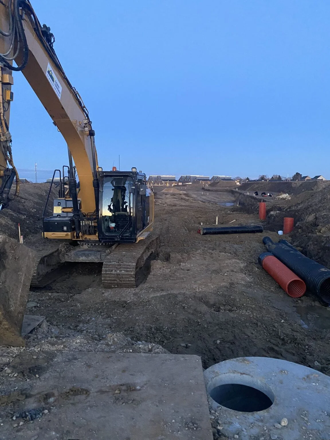 Gravemaskine arbejder på byggeplads med rørinstallation