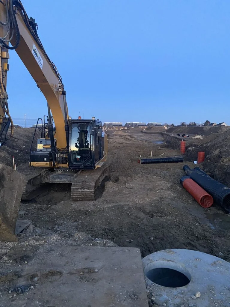 Gravemaskine arbejder på byggeplads med rørinstallation
