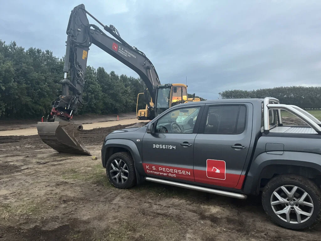 Entreprenørbil og gravemaskine på byggeplads