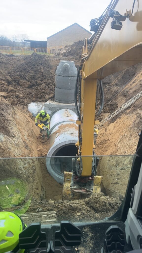 Entreprenørarbejde med gravemaskine og betonrørinstallation