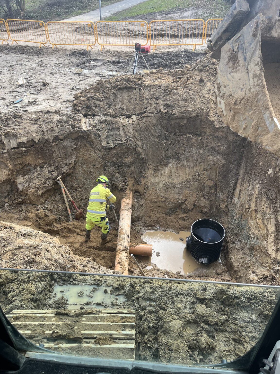 Arbejder reparerer kloakrør i dyb muddergrav