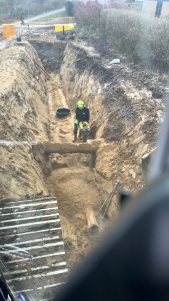 Arbejder graver dyb grøft til rørinstallation